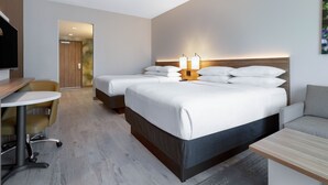 Une chambre d’hôtel moderne avec deux lits, un bureau et une chaise.