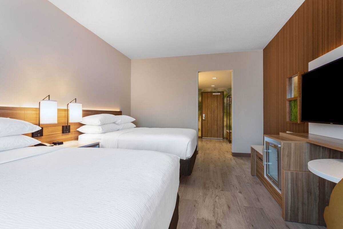 Una habitación de hotel con dos camas, televisión, escritorio y baño.