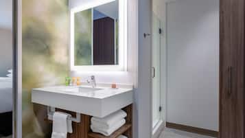 A modern bathroom with a large mirror, two sinks, and a shower.