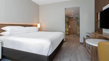 Ein modernes Hotelzimmer mit einem großen Bett, einem Schreibtisch und einem Fernseher.