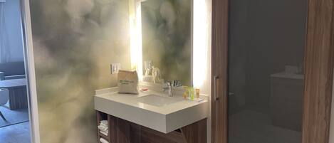 A bathroom with a modern design, featuring a wooden vanity, a large mirror, and a shower area.
