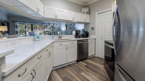 A modern kitchen with white cabinets, a stainless steel refrigerator, and a dishwasher. - 46 Ocean Breeze: Luxury Villa, Newly Updated, Pet Friendly, Free Bikes (Hilton Head Island)