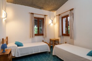 A room with two single beds, a wooden nightstand with a lamp, and a small wooden chair. - Casa Lisa (Olbia)