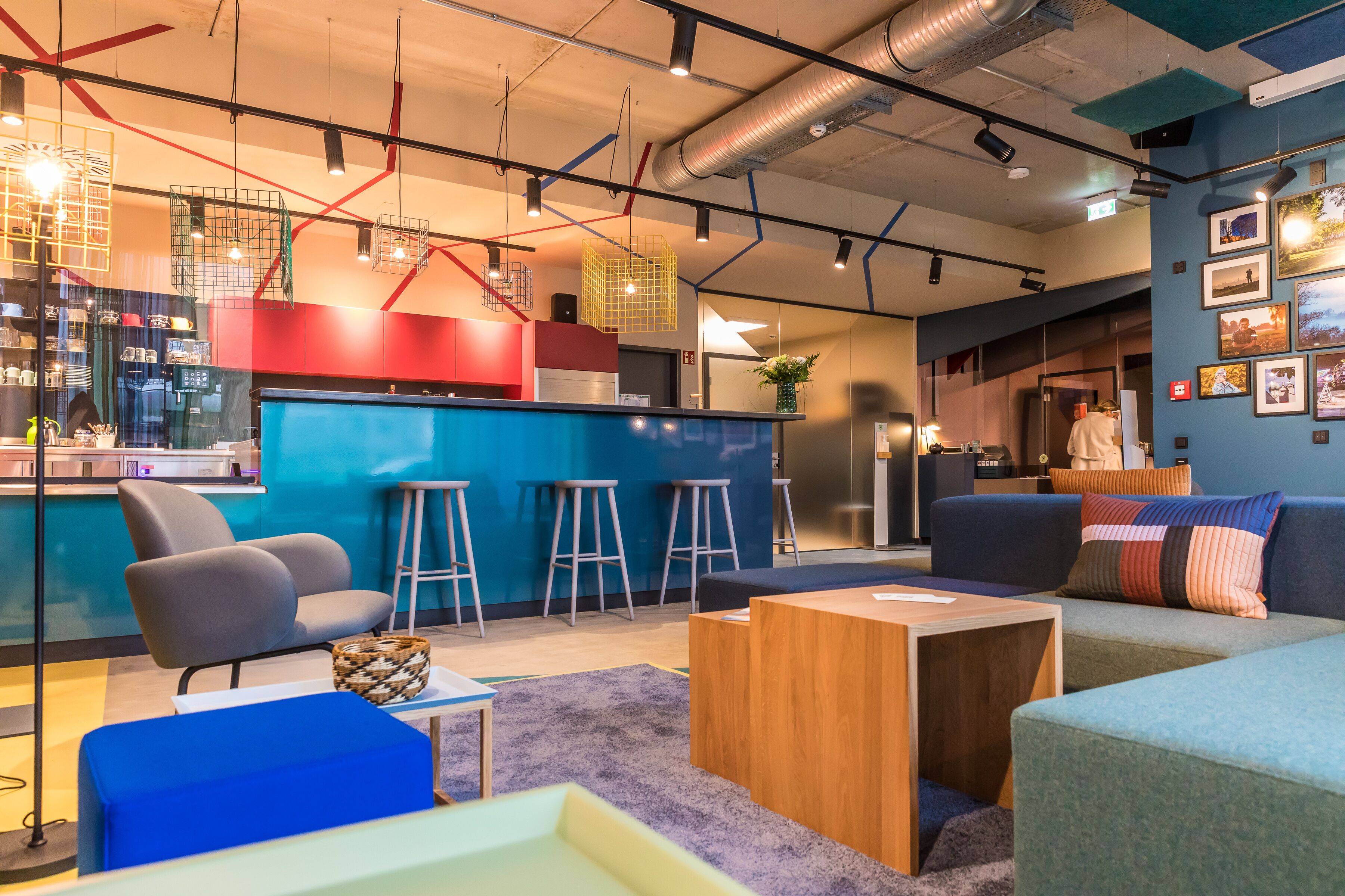 Un espace de détente moderne avec un bar, des sièges et une cuisine en arrière-plan.