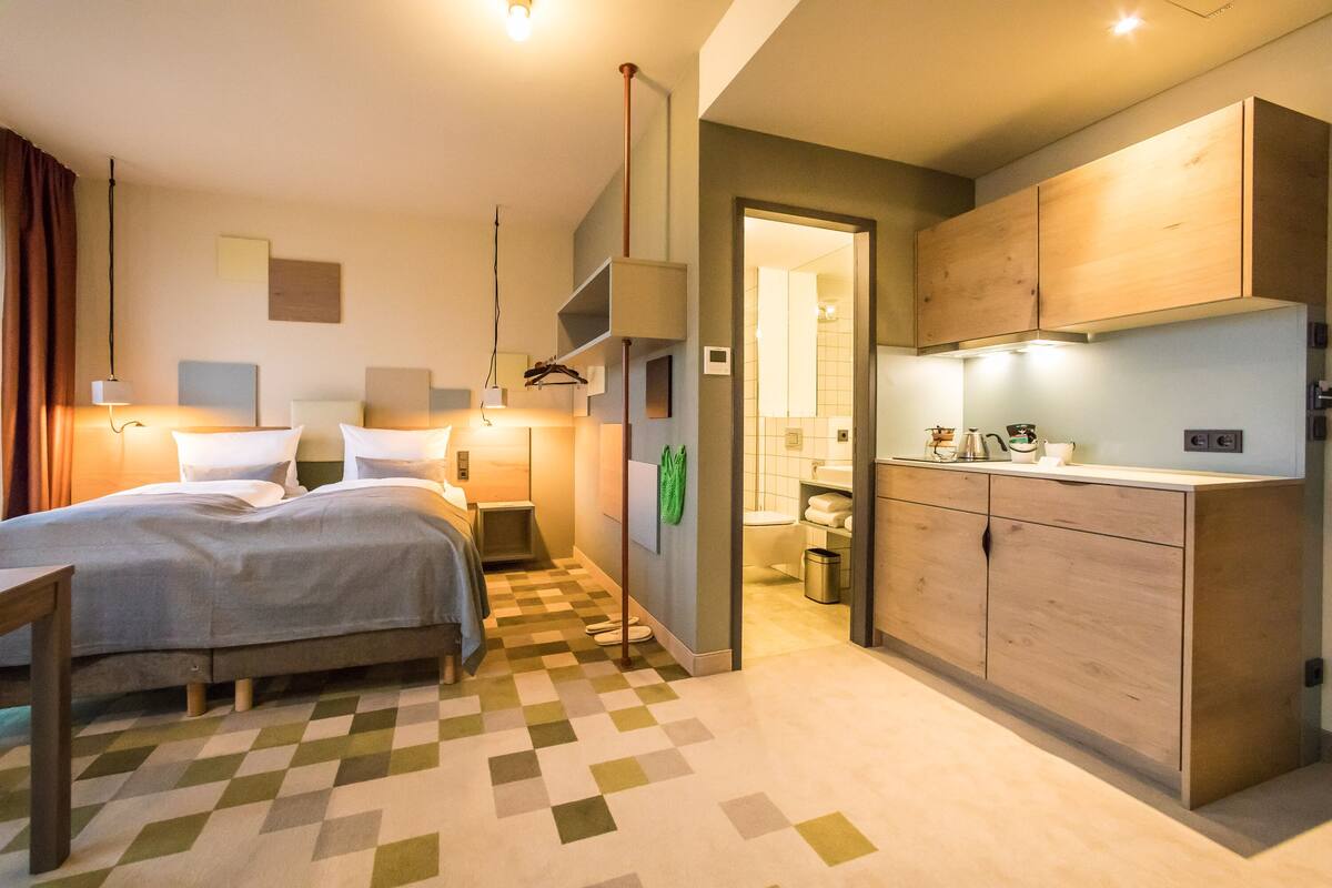 Une chambre d’hôtel avec un lit, une table de chevet, une lampe et un sol à carreaux.