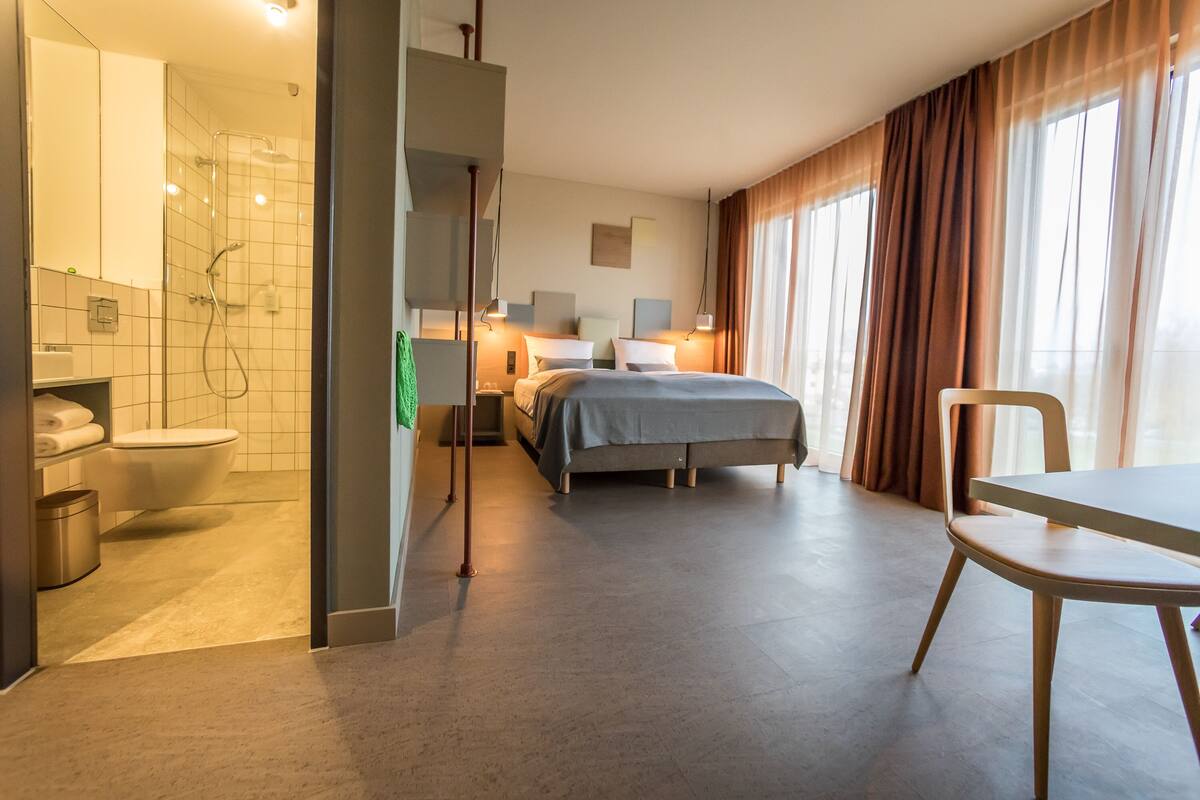 Une chambre d’hôtel équipée d’une douche, de toilettes, d’un lit et d’un coin repas.