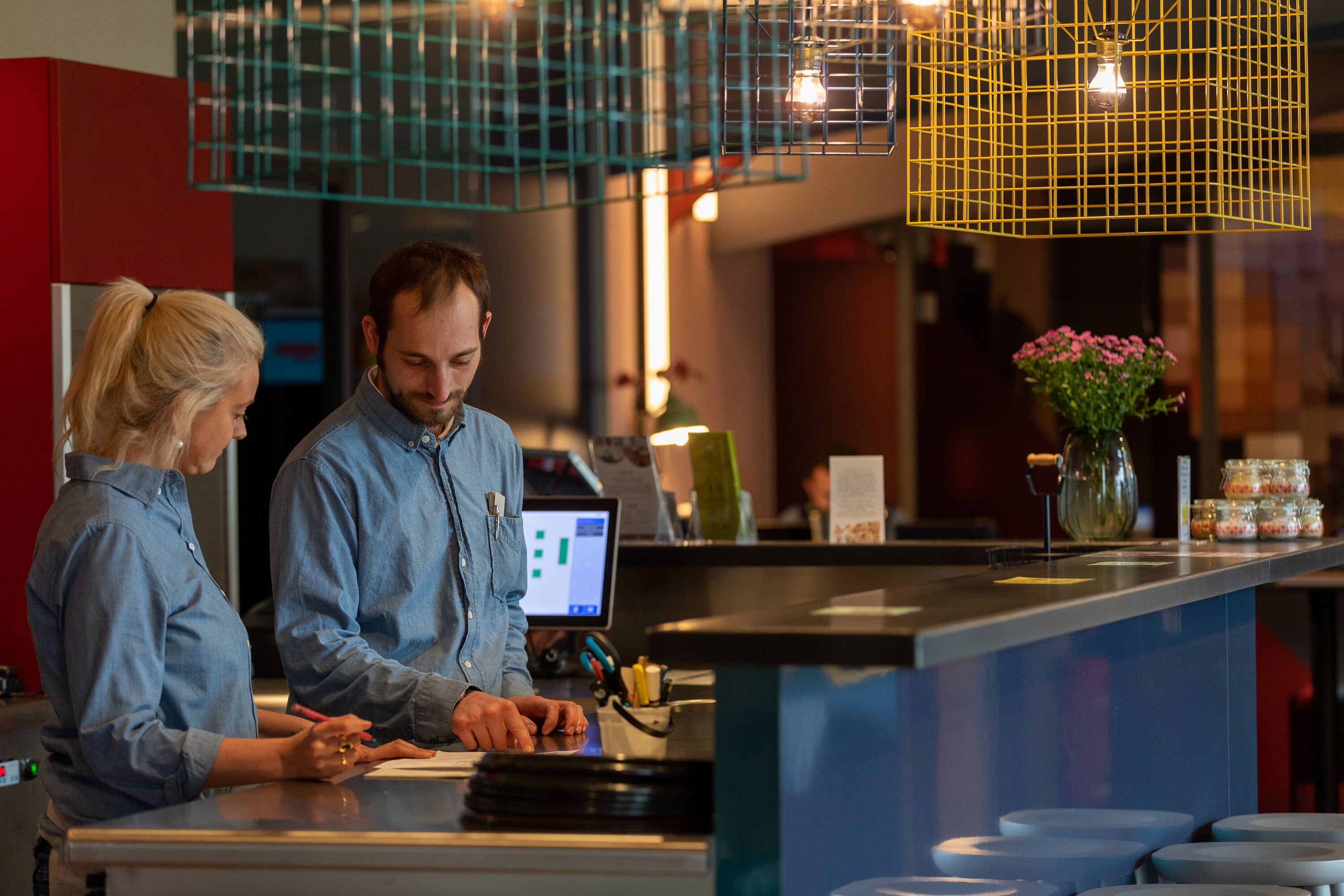 A modern bar area with a counter, bar stools, and a decorative hanging light fixture.