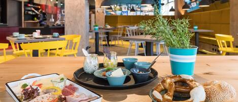 Un comedor con una mesa de madera, sillas amarillas y una taza azul y blanca a rayas.