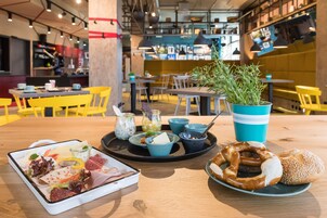 Un comedor con una mesa de madera, sillas amarillas y una taza azul y blanca a rayas.