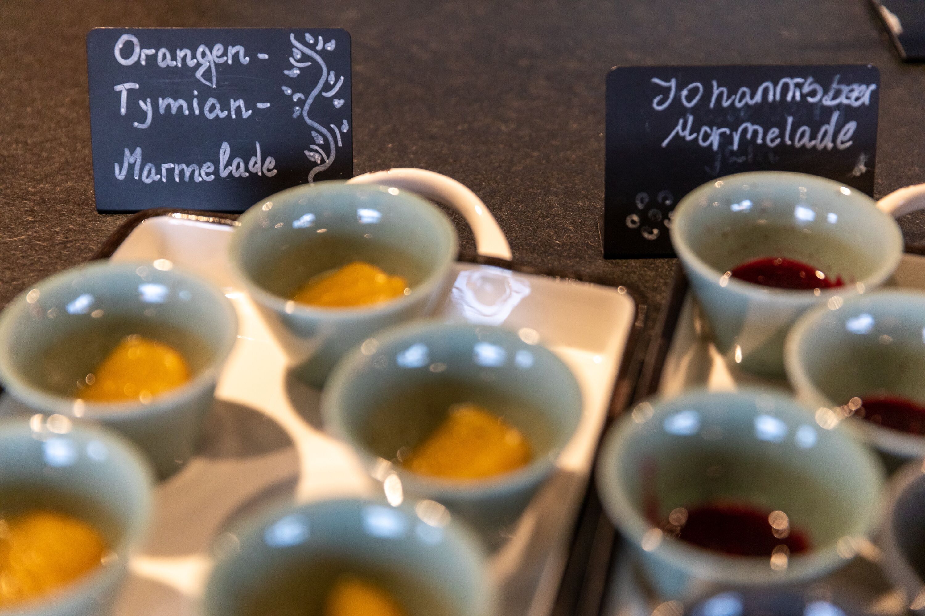 Een assortiment kleine schaaltjes met verschillende sauzen en een bordje met de tekst 'Marmelade'.