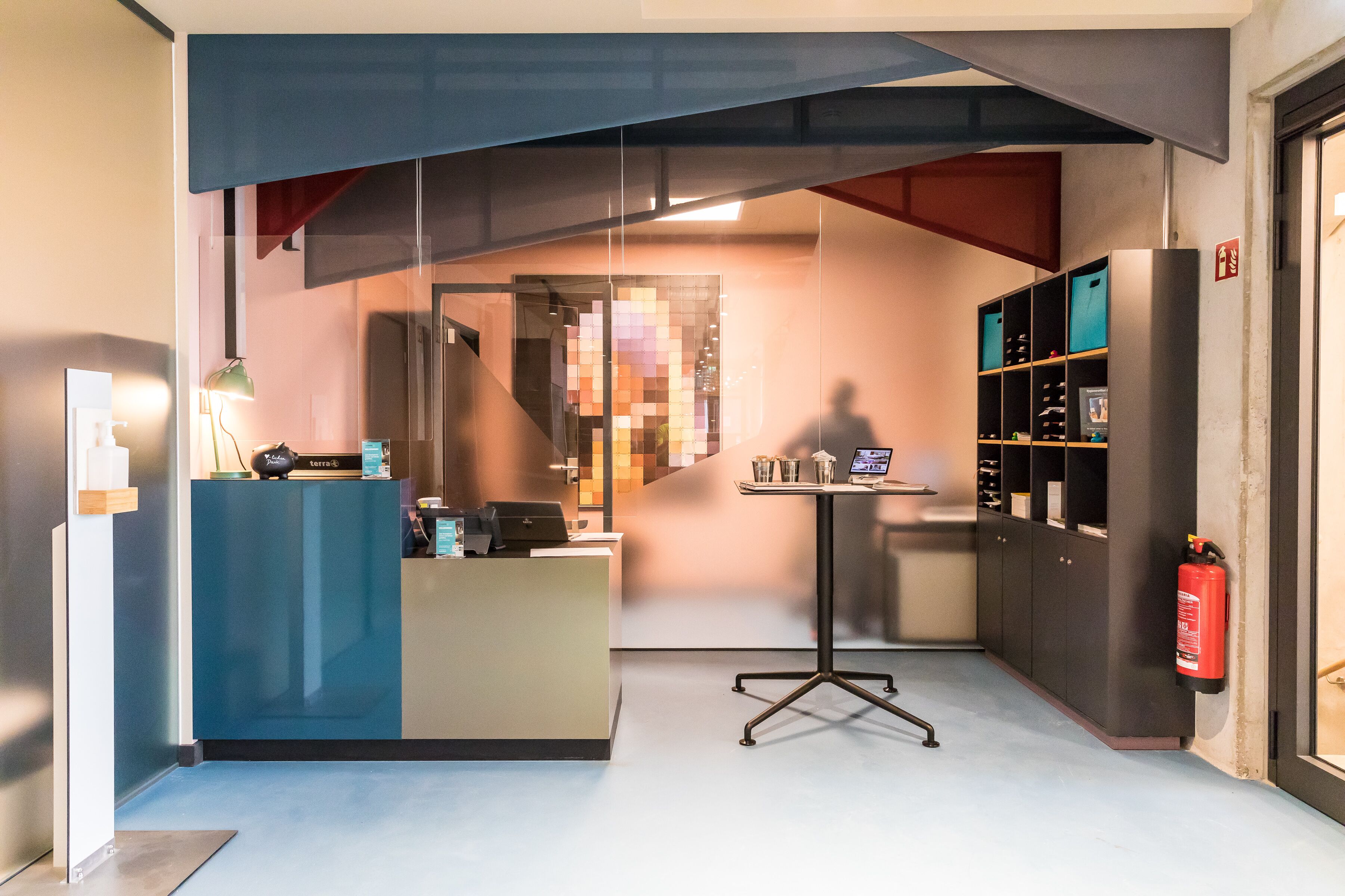 A modern reception area with a desk, computer, and shelves.