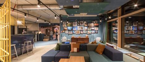 A modern lounge area with a large sectional sofa, a wooden coffee table, and a bar area with stools.