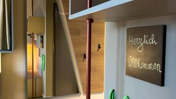 A modern interior with a wooden ceiling, a mirror, a welcome sign, and a green towel hanging on the wall.