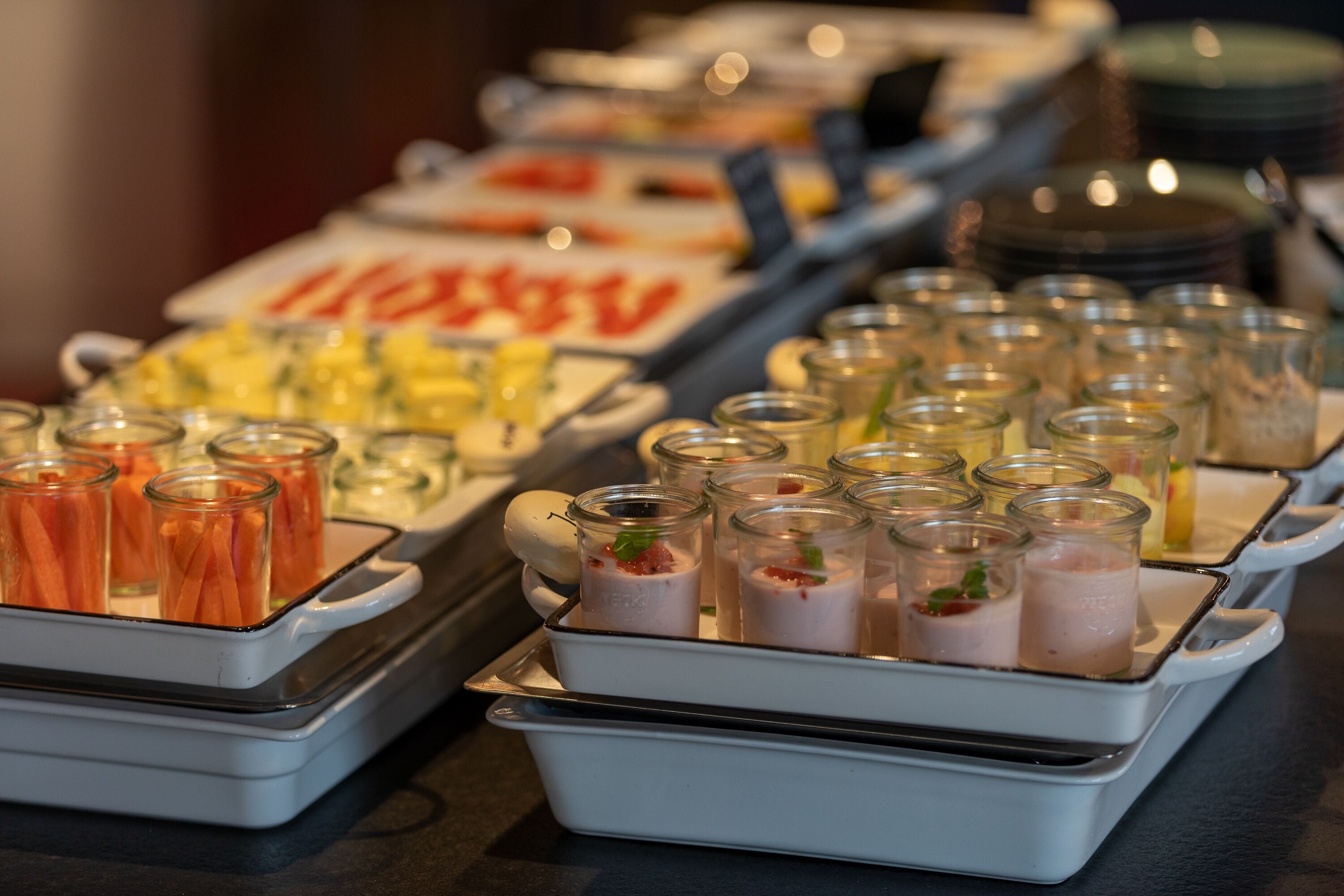 Un buffet proposant une variété de plats et de boissons présentés dans des récipients en verre.