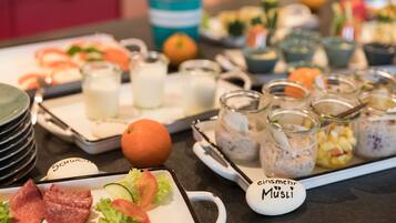 Un bufé con diversos alimentos, incluyendo carnes, ensaladas y bebidas.