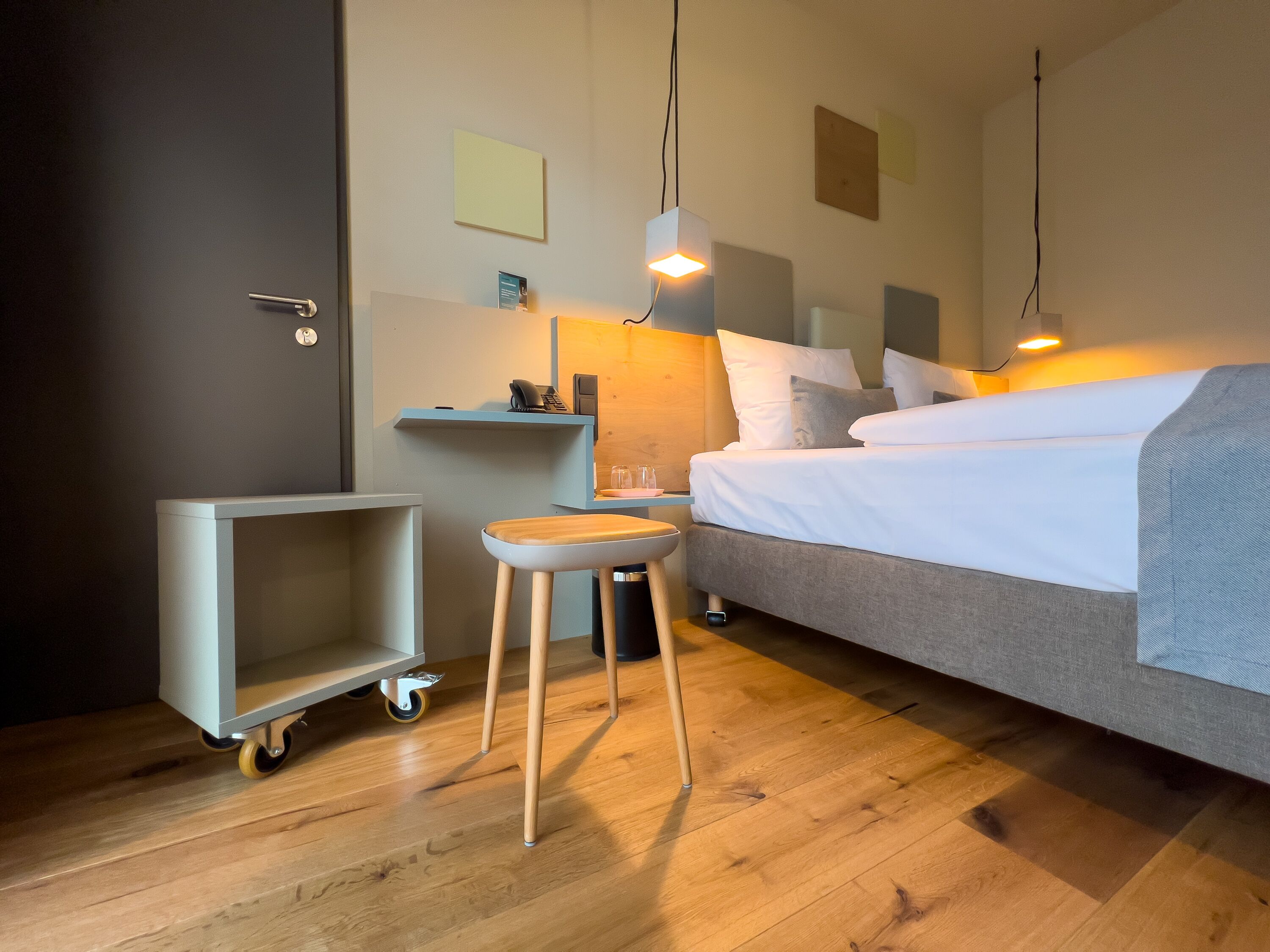 Una habitación de hotel con una cama, un escritorio, una silla y un carrito.