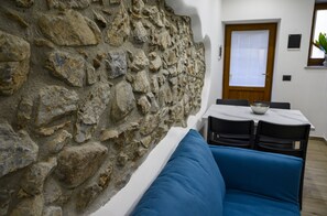 A room with a stone wall, a white table with a bowl, and a blue sofa.