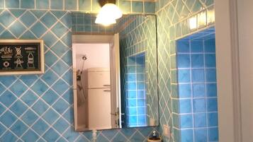A bathroom with blue patterned tiles, a white sink, a mirror, and a framed picture on the wall.