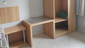 A room with a wooden bed, a small wooden bench, and a tiled floor. - Hotel Mime (Blumenau)