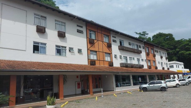 A multi-story hotel with a white facade, brown accents, and a tiled roof. - Hotel Mime (Blumenau)