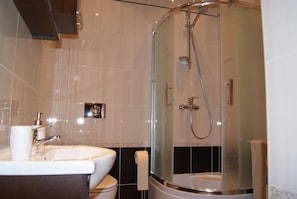 A modern bathroom with a glass-enclosed shower, a sink, and a toilet. - Gdańskie Apartamenty - Długa (Gdansk)