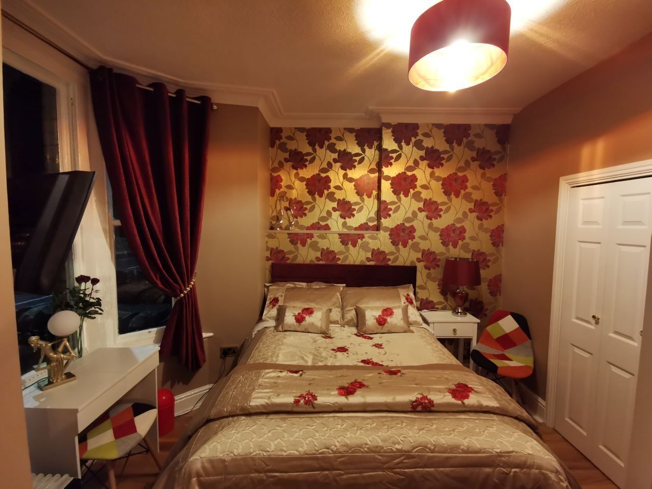 A bedroom with a bed, a nightstand, a lamp, a chair, and a wardrobe.
