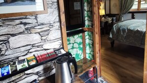 Habitació rústica amb una paret de pedra, un quadre amb marc, una taula de fusta amb una papereta i un llit amb dosser.