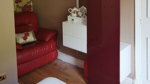 Una habitació amb un sofà de pell vermella, un aparador blanc, un mirall i una porta vermella.