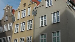 A building with a sign reading "LEZZETTI" and a black car parked in front. - Gdańskie Apartamenty Gdańskie Poddasza (Gdansk)