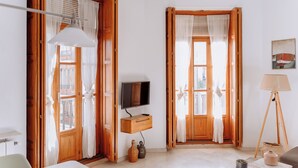 Ein Zimmer mit Holztüren, einem Fernseher auf einem Holzregal, einer Stehlampe und einem Bild an der Wand.