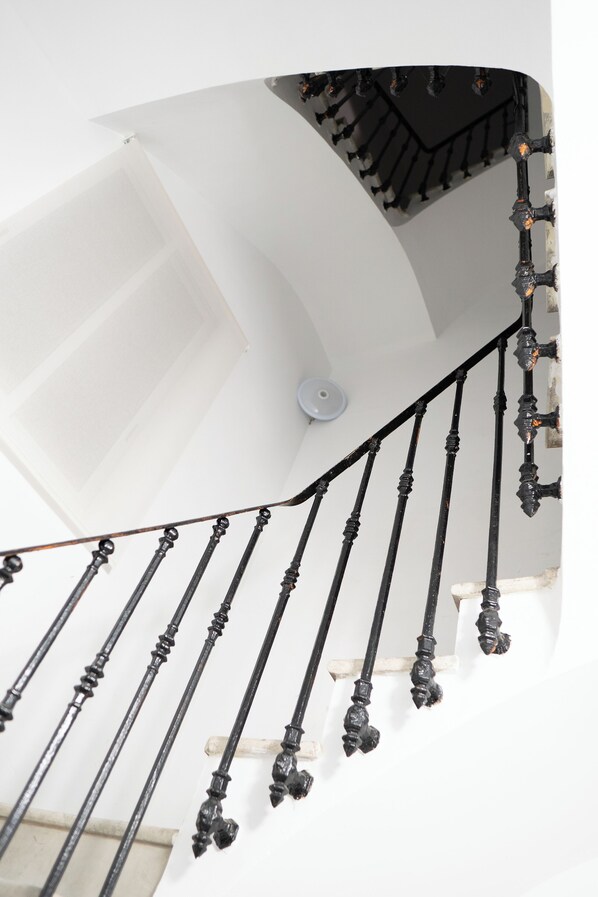 Eine geschwungene Treppe mit aufwendiger schwarzer Spindel und weißen Wänden.
