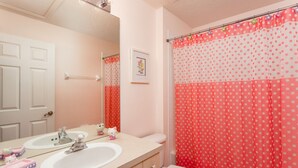 A bathroom with a white sink, a mirror, a toilet, and a shower curtain with a polka dot pattern. - Windsor Palms-ru1025 (Kissimmee)