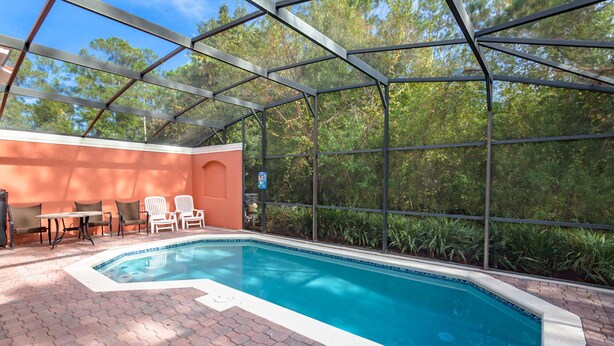 A covered outdoor swimming pool with a brick patio, lounge chairs, and a table. - Terra Verde-ru1056 (Kissimmee)