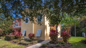A two-story building with a beige exterior, white shutters, and a small porch area. - Terra Verde-ru1056 (Kissimmee)