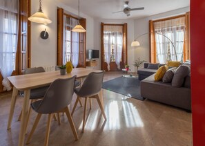 Una sala de estar moderna con comedor, ventanas amplias y ventilador de techo.