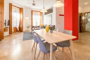 A modern dining area with a wooden table, blue chairs, and a red accent wall. - LOVELY APARTMENT SERRANOS TOWERS (València)