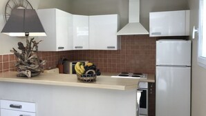 A modern kitchen with white cabinets, a built-in stove, and a refrigerator.