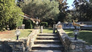 A stone staircase leading up to a house with a hammock and a fence in the background.