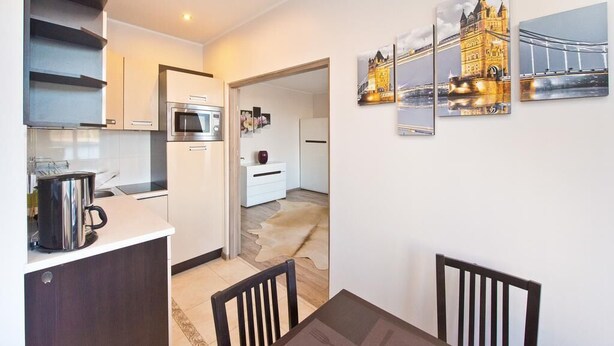 A modern kitchen with a built-in oven and a coffee maker on the counter. There are three framed pictures on the wall depicting a bridge and a castle. - Gdańskie Apartamenty Targ Rybny Mołtawa (Gdansk)