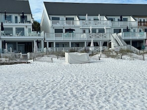 Un hotel frente a la playa con varios balcones, un área de estar al aire libre techada y una playa de arena.