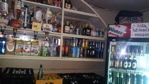 En købmandsbutik med hylder fyldt med forskellige alkoholholdige drikkevarer, herunder flasker, dåser og kasser.