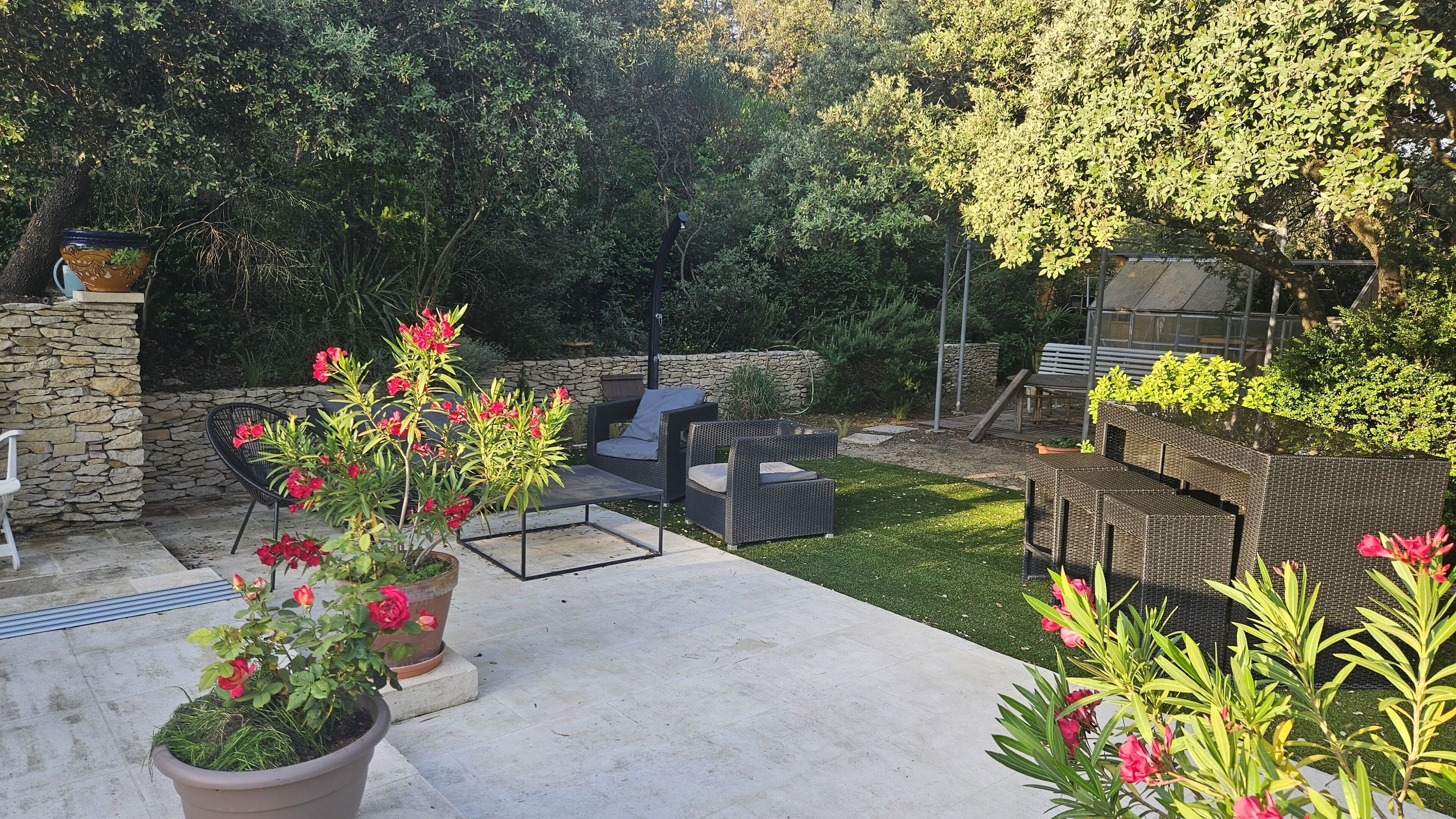 An outdoor patio with wicker furniture, a stone wall, and potted plants.