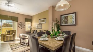 Un coin repas avec une table en bois, des chaises noires et une plante décorative en guise de centre de table.