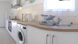 Une cuisine moderne équipée d’un lave-linge, un coin repas avec une table ronde et des chaises, et un canapé.