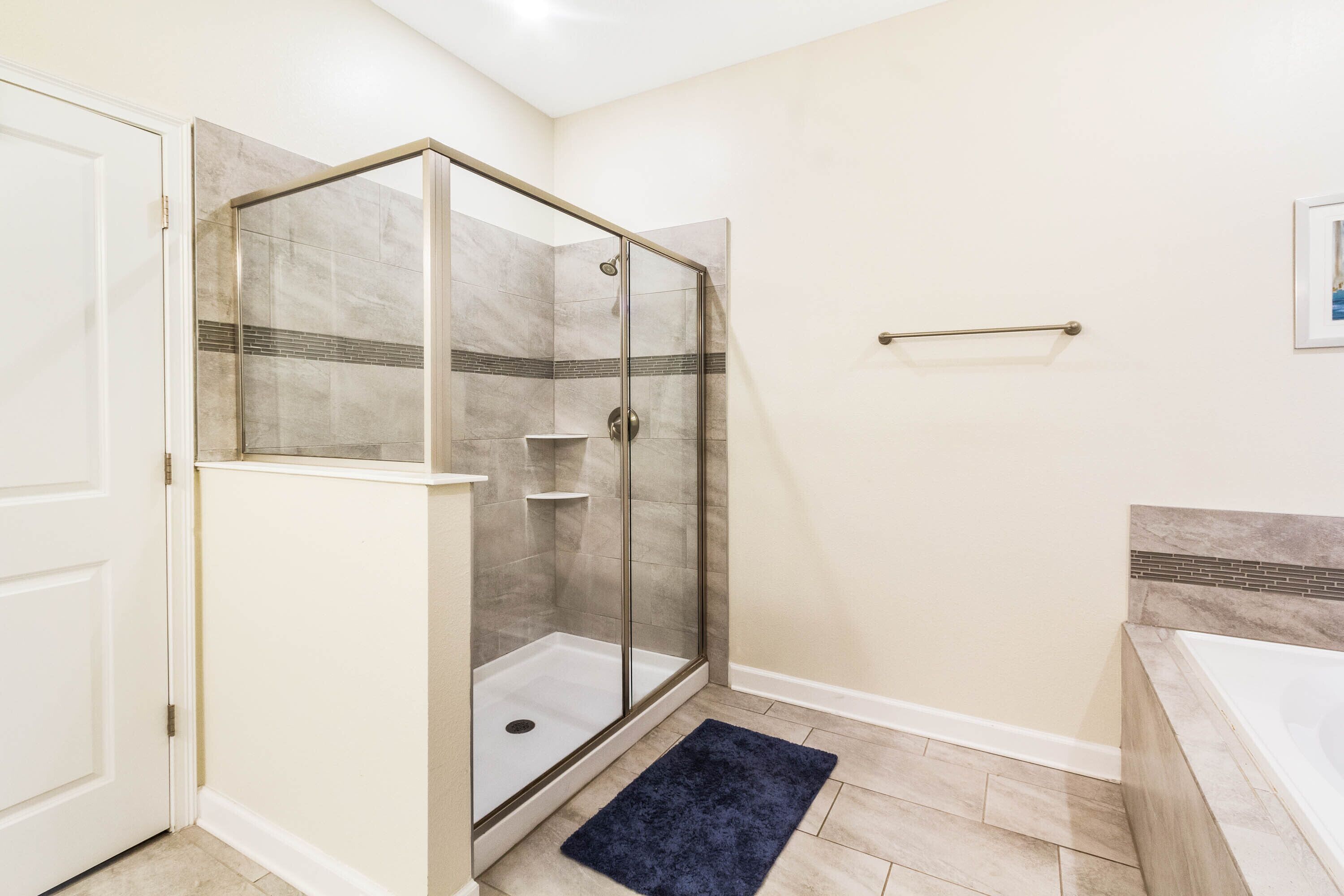 Une salle de bain avec une douche à parois de verre, une baignoire et une porte blanche.