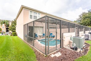 Uma casa com um alpendre envidraçado, piscina e unidades de ar condicionado ao ar livre.