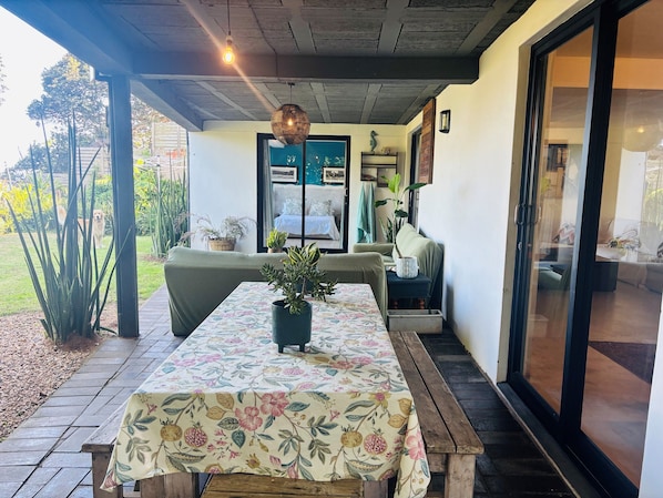 Un patio couvert avec une table en bois, un canapé et une plante en pot.