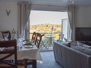 Ein Essbereich mit einem Tisch für zwei Personen, einer Couch und einem Fernseher.