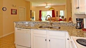 A kitchen with white cabinets, a granite countertop, a dishwasher, and a stove.