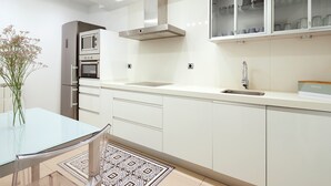 Une cuisine moderne avec des meubles blancs, une hotte en acier inoxydable et un four encastré.